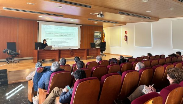 Desayuno informativo en Boltaña sobre comunidades energéticas Ponente de la Oficina de Transformación Comunitaria (OTC) Aragón Energía Propia exponiendo información sobre comunidades energéticas a los asistentes en un auditorio en Boltaña.