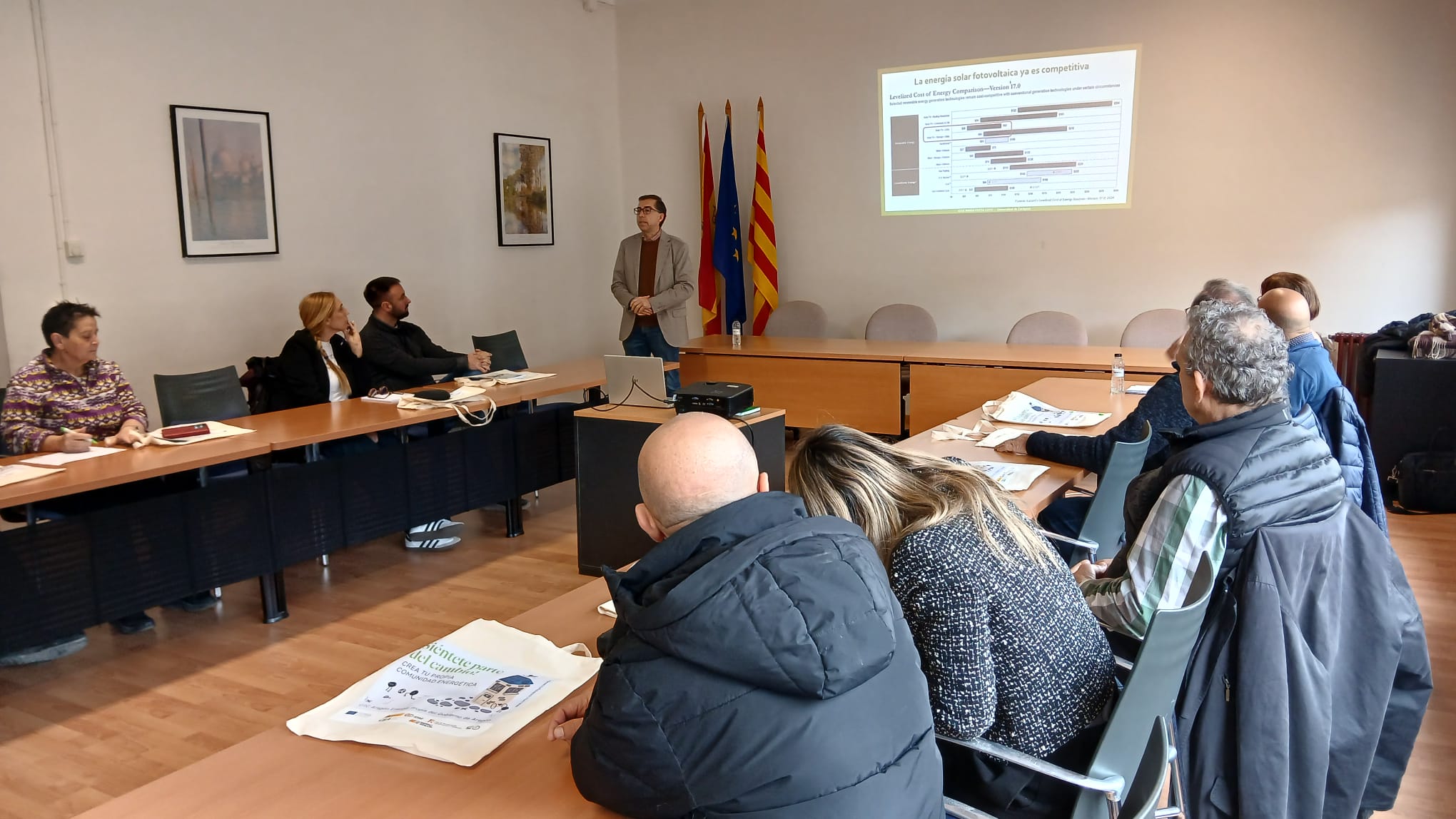 Personas asistiendo a una jornada informativa sobre comunidades energéticas en Tamarite de Litera, con un ponente explicando el impacto de las energías renovables